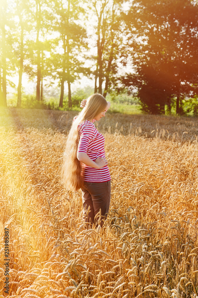 A girl with long hair stands on a field with a niche. A girl with long hair stands on a field with a niche.