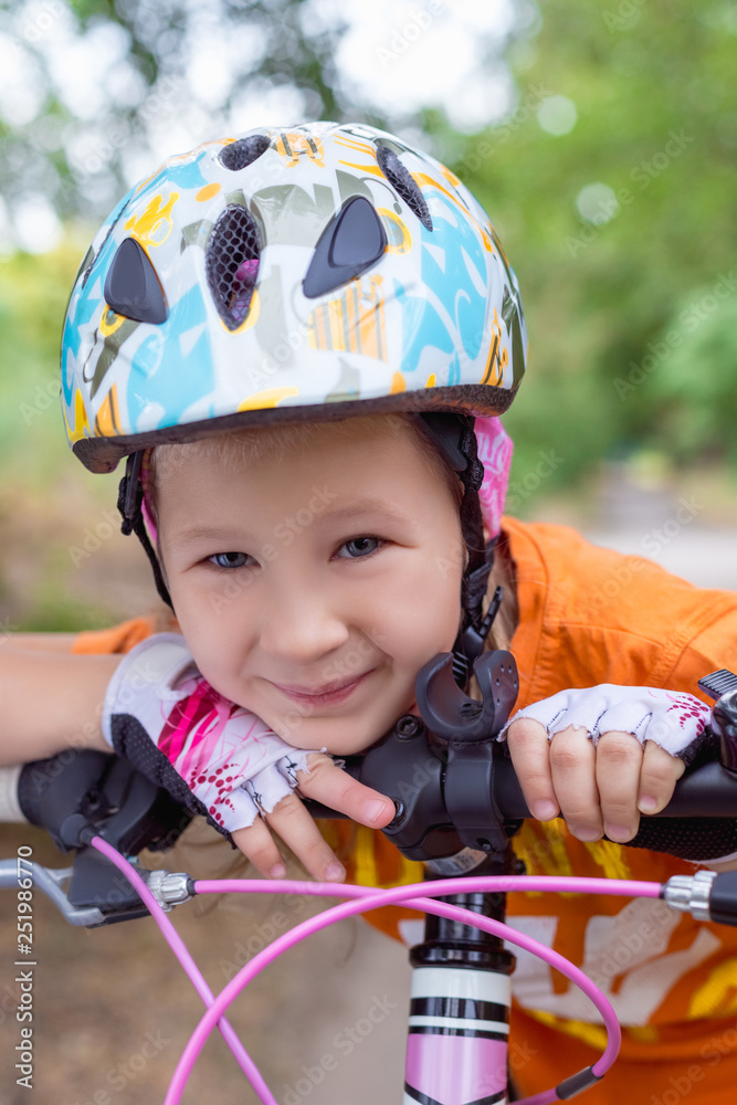 Cute little girl in a helmet with a bike in the summer Cute little girl in a helmet with a bike in the summer