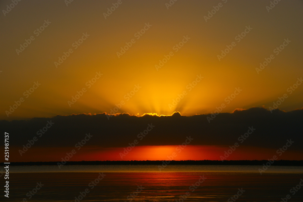 sunrise on a big lake. The sun's rays shine through the clouds