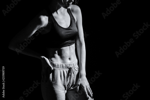 Black and white photo of sporty young woman on dark background