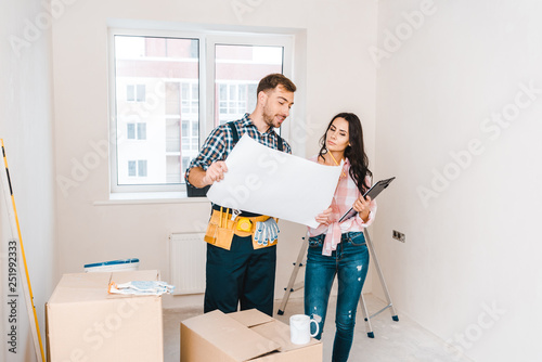 cheerful handyman holding blueprint near attractive client