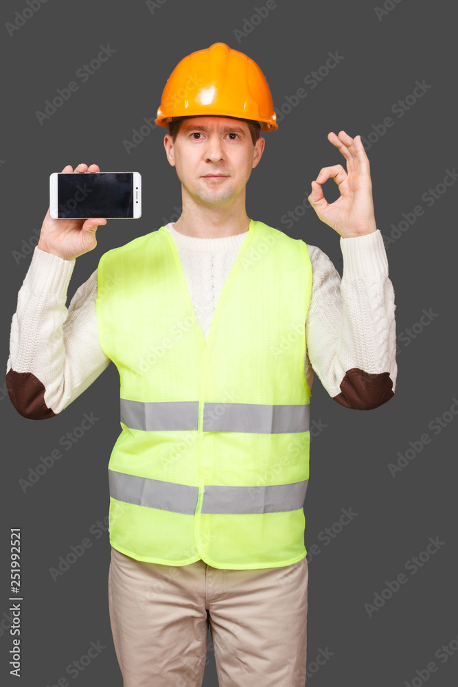 the man in a helmet with phone, shows gesture OK, everything is good the man in a helmet with phone, shows gesture OK, everything is good
