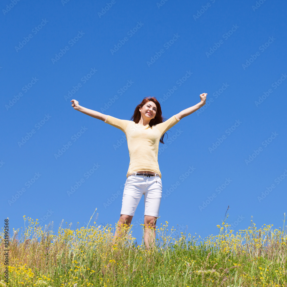 People freedom success concept. Happy woman dreams to fly on winds. Landscape of grass and flower summer field on sunny day. Nature beauty background, blue sky and green meadow. Outdoor lifestyle.
