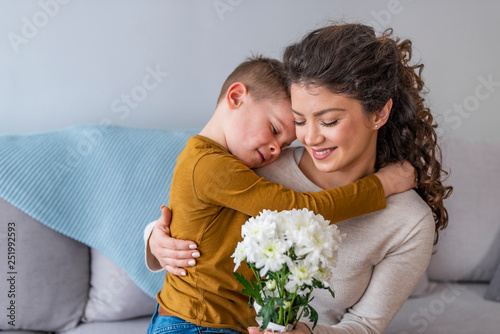 Mother and her little son with bouquet of flowers, Happy family mom and kid kissing and hugging. Mother's day gift.