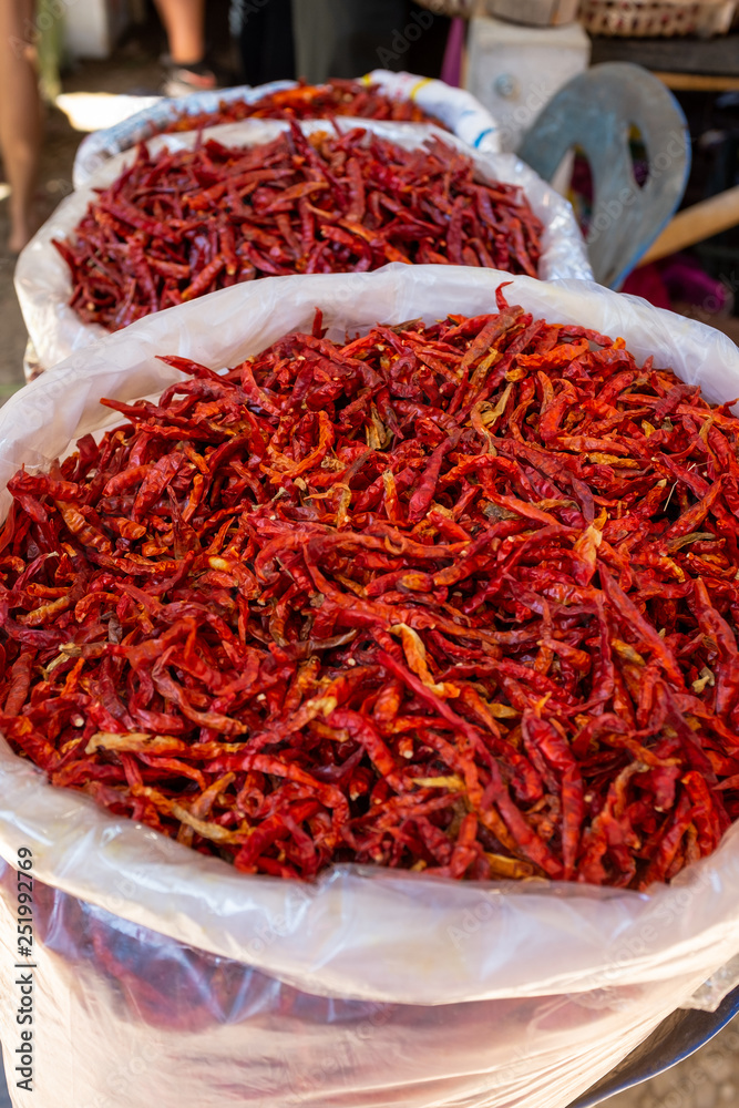 Naklejka premium Bags of bright red dried chillis for sale at an Asian food market.