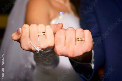 Fists of cheerful newlyweds with golden rings, close-up
