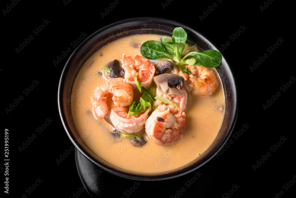 Φωτογραφία Spicy Thai soup Tom Yam with Coconut milk, Chili pepper and Seafood shrimp and salmon in a plate on a black background