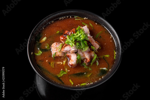 Hot miso soup with seaweed, smoked eel in bowl on black background. Japanese food.