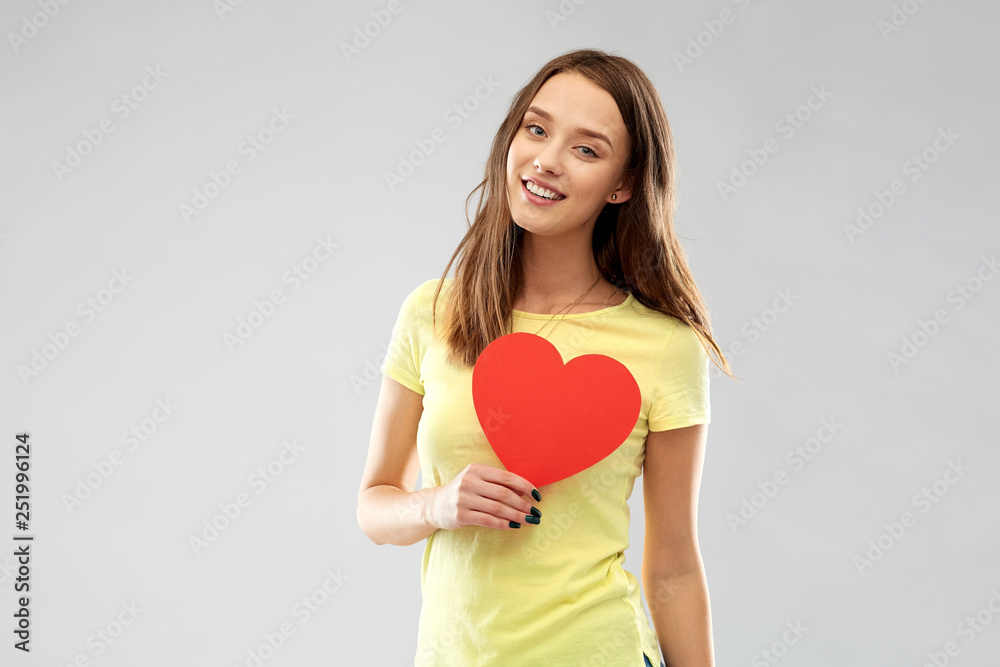 valentine's day and people concept - smiling young woman or teenage girl in yellow t-shirt with red heart over grey background valentine's day and people concept - smiling young woman or teenage girl in yellow t-shirt with red heart over grey background