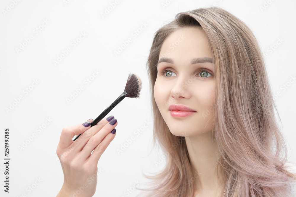Make-up artist makes makeup beautiful blonde girl on a white background. Close-up hands with brush and face. Make-up artist makes makeup beautiful blonde girl on a white background. Close-up hands with brush and face.