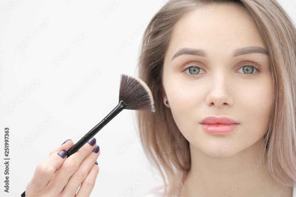 Make-up artist makes makeup beautiful blonde girl on a white background. Close-up hands with brush and face. Make-up artist makes makeup beautiful blonde girl on a white background. Close-up hands with brush and face.