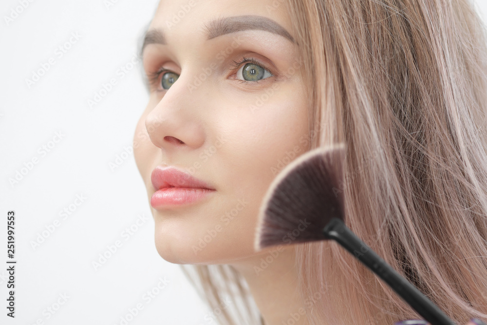 Make-up artist makes makeup beautiful blonde girl on a white background. Close-up hands with brush and face. Make-up artist makes makeup beautiful blonde girl on a white background. Close-up hands with brush and face.