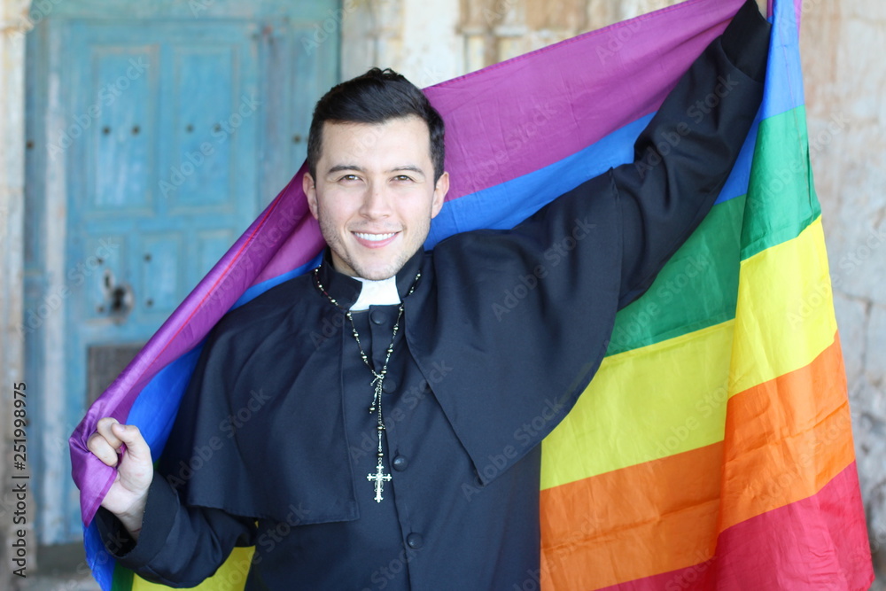 Priest holding the rainbow flag Stock Photo