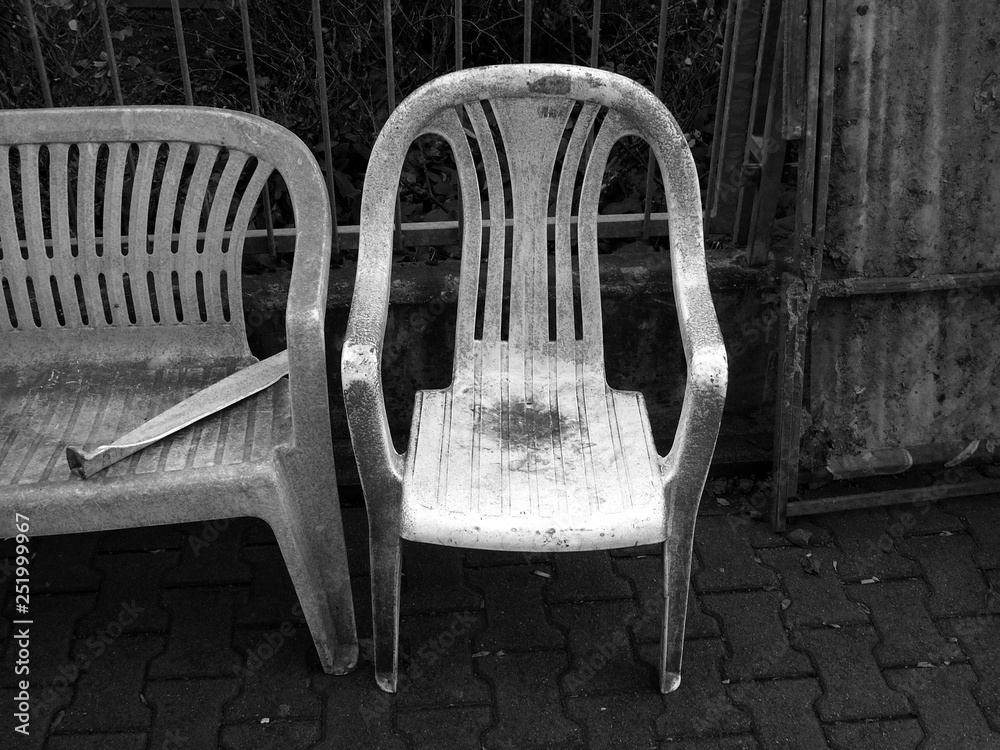 Schmutziger alter Plastikstuhl und Gartenmöbel als Sperrmüll auf dem  Bürgersteig und Gehweg im Westend von Frankfurt am Main in Hessen,  fotografiert in neorealistischem Schwarzweiß Stock-Foto | Adobe Stock