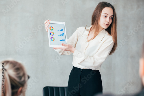 Data analysis. Business matters. Smiling woman teamlead representing diagrams in tablet. photo