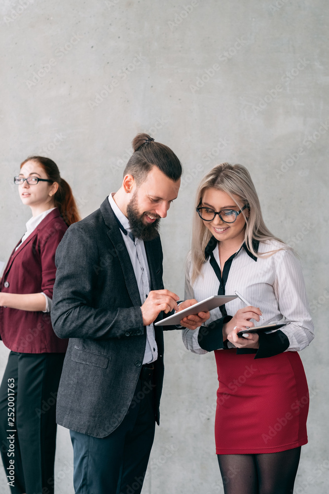 Business feedback reviews. Close colleagues. Smiling team members browsing tablet. Copy space on grey background. Business feedback reviews. Close colleagues. Smiling team members browsing tablet. Copy space on grey background.