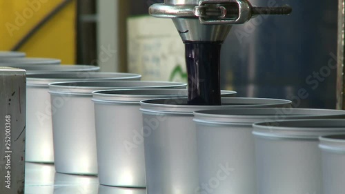 tap filling black paint into metal cans at factory, oil paint factory producing paint