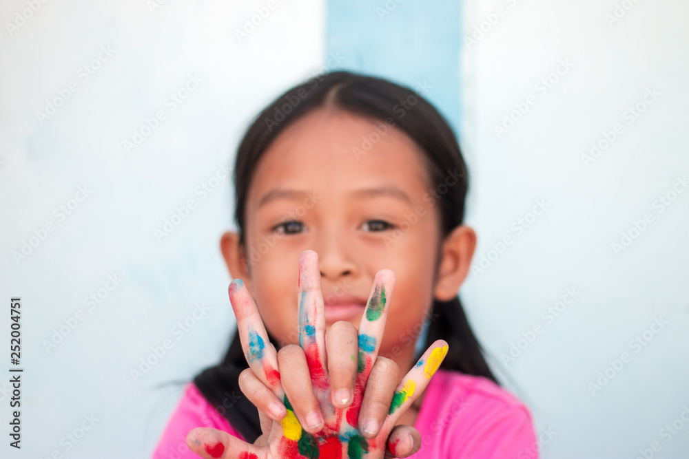 Cute little girl with colorful painted hands on wall background Cute little girl with colorful painted hands on wall background