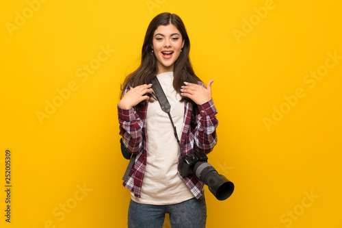 Photographer teenager girl over yellow wall with surprise facial expression © luismolinero