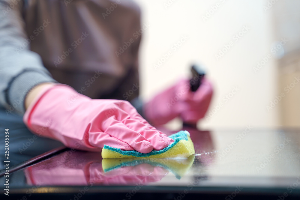 Photo of woman's hands in pink glove with sponge and spray washing oven .