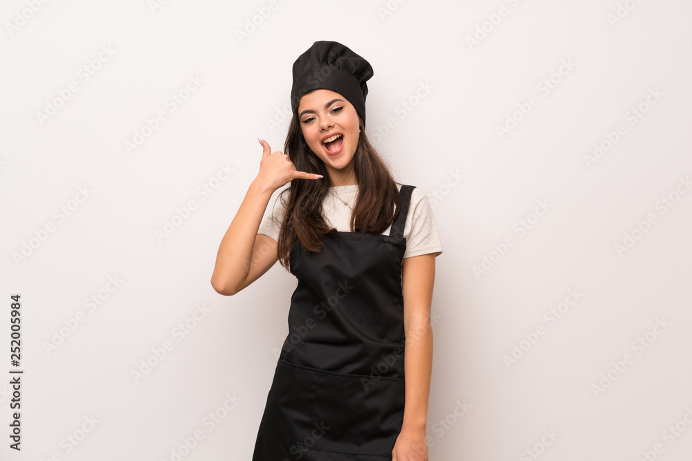 Teenager chef over white wall making phone gesture. Call me back sign Teenager chef over white wall making phone gesture. Call me back sign