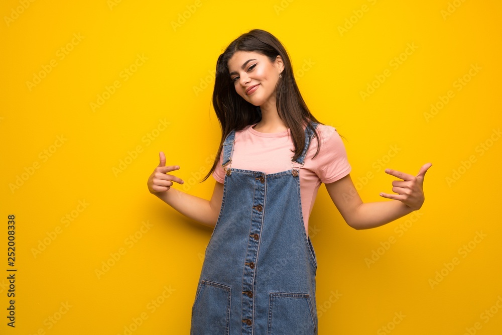 Teenager girl over yellow wall proud and self-satisfied Teenager girl over yellow wall proud and self-satisfied