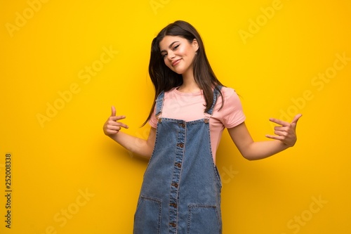 Teenager girl over yellow wall proud and self-satisfied