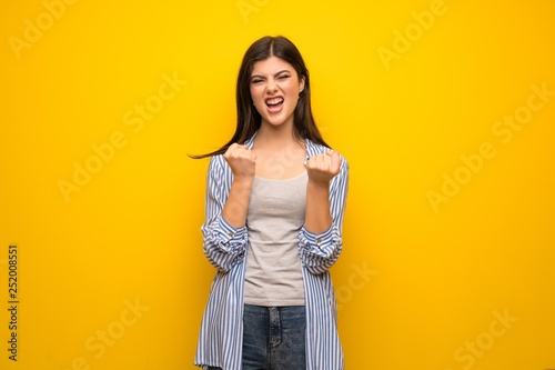 Teenager girl over yellow wall frustrated by a bad situation