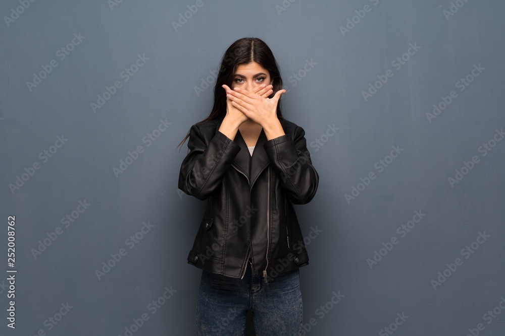 Teenager girl over grey wall covering mouth with hands for saying something inappropriate Teenager girl over grey wall covering mouth with hands for saying something inappropriate