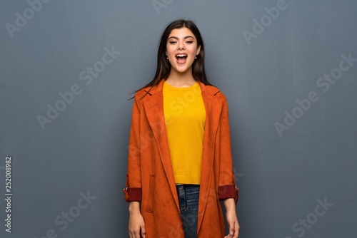 Teenager girl with coat over grey wall with surprise facial expression © luismolinero