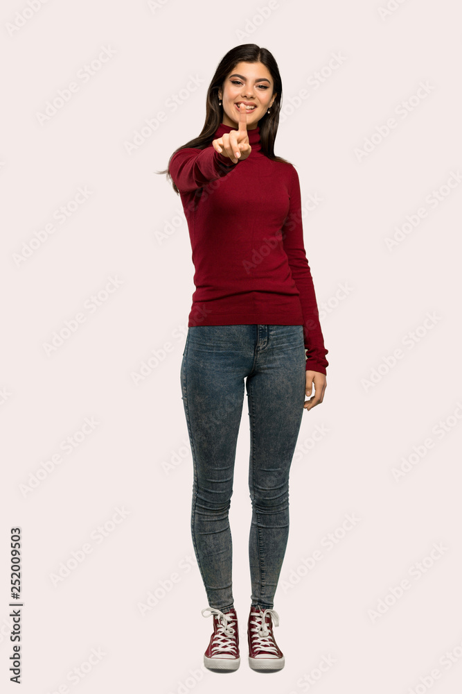 A full-length shot of a Teenager girl with turtleneck showing and lifting a finger over isolated background A full-length shot of a Teenager girl with turtleneck showing and lifting a finger over isolated background