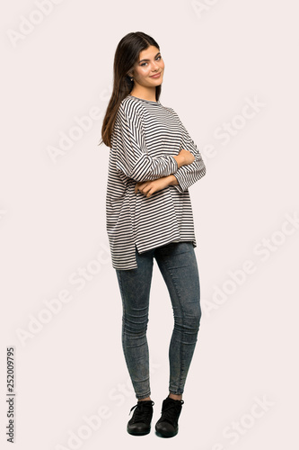 A full-length shot of a Teenager girl with striped shirt with arms crossed and looking forward over isolated background