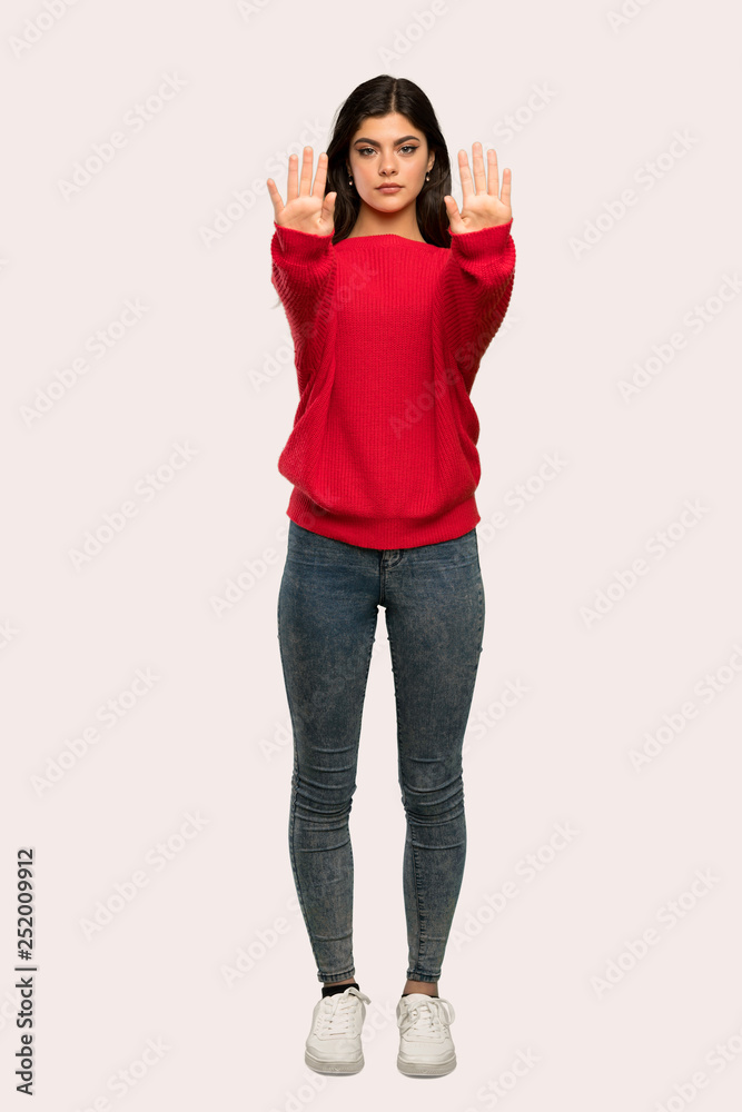 A full-length shot of a Teenager girl with red sweater making stop gesture and disappointed over isolated background A full-length shot of a Teenager girl with red sweater making stop gesture and disappointed over isolated background