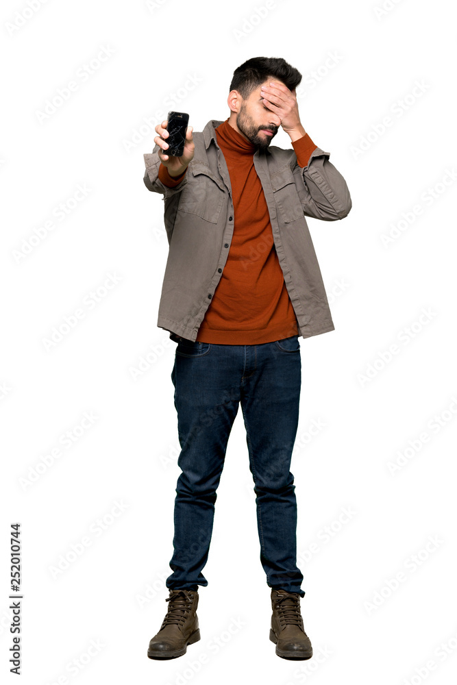 Full-length shot of Handsome man with beard with troubled holding broken smartphone on isolated white background Full-length shot of Handsome man with beard with troubled holding broken smartphone on isolated white background