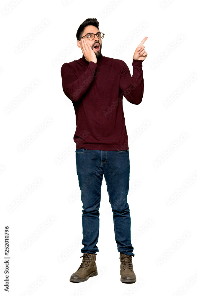 Full-length shot of Handsome man with glasses pointing up and surprised on isolated white background Full-length shot of Handsome man with glasses pointing up and surprised on isolated white background