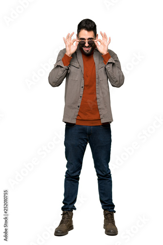 Full-length shot of Handsome man with beard with glasses and surprised on isolated white background