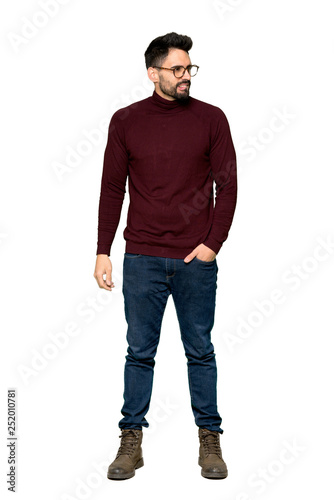 Full-length shot of Handsome man with glasses with confuse face expression while bites lip on isolated white background © luismolinero