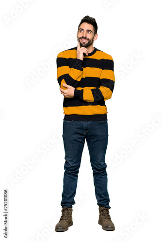 Full-length shot of Handsome man with striped sweater thinking an idea while looking up on isolated white background