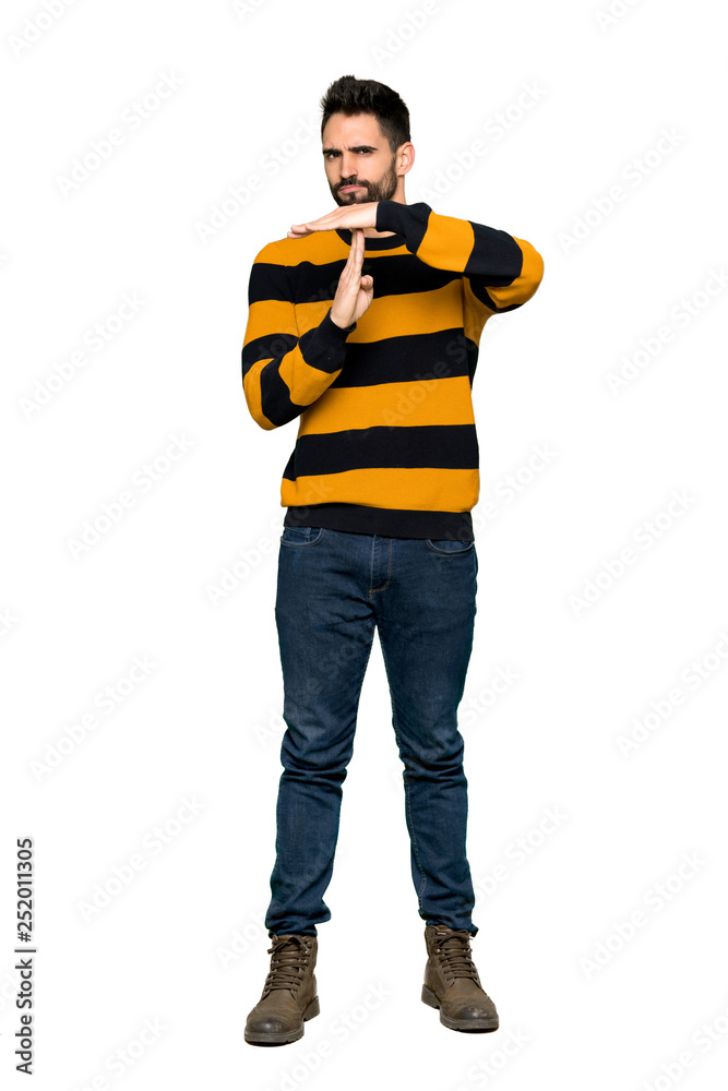 Full-length shot of Handsome man with striped sweater making stop gesture with her hand to stop an act on isolated white background Full-length shot of Handsome man with striped sweater making stop gesture with her hand to stop an act on isolated white background
