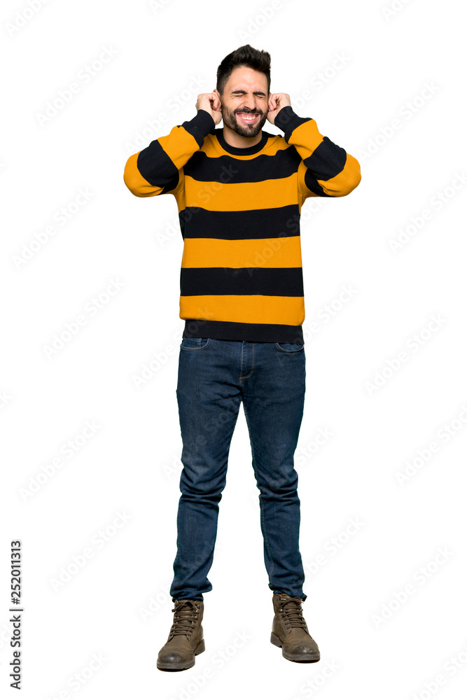 Full-length shot of Handsome man with striped sweater covering ears with hands. Frustrated expression on isolated white background Full-length shot of Handsome man with striped sweater covering ears with hands. Frustrated expression on isolated white background