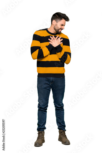 Full-length shot of Handsome man with striped sweater having a pain in the heart on isolated white background