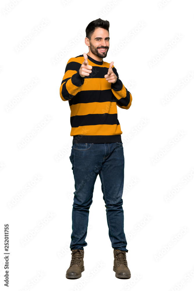Full-length shot of Handsome man with striped sweater pointing to the front and smiling on isolated white background Full-length shot of Handsome man with striped sweater pointing to the front and smiling on isolated white background