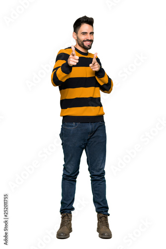 Fototapeta Naklejka Na Ścianę i Meble -  Full-length shot of Handsome man with striped sweater pointing to the front and smiling on isolated white background