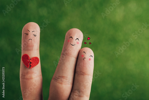 cropped view of fingers as happy couple in love and third wheel with broken heart on green