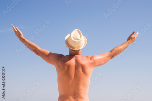 Man Raising His Hands or Open arms standing back looking to sea blue sky horizon. Strong muscular Men, perfect body, arms, back. Freedom Concept © Dragana Gordic