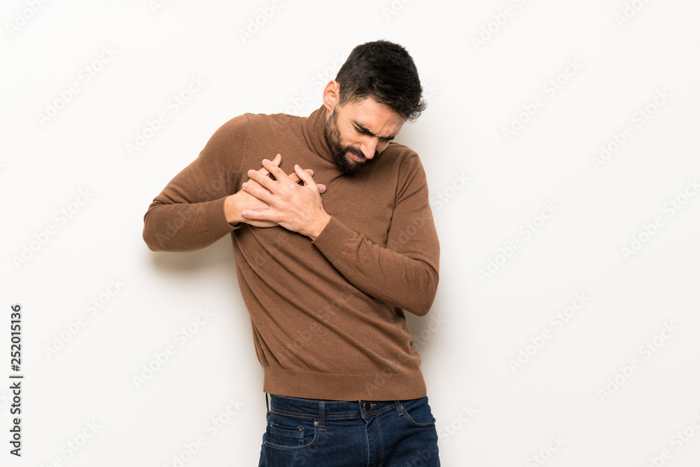 Handsome man over white wall having a pain in the heart Handsome man over white wall having a pain in the heart