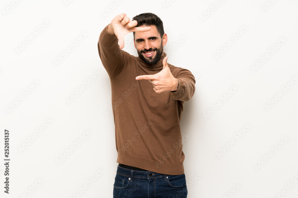 Handsome man over white wall focusing face. Framing symbol Handsome man over white wall focusing face. Framing symbol