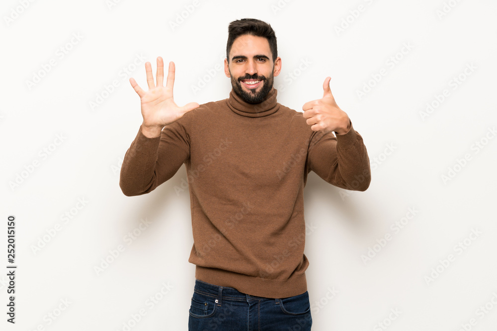 Fototapeta premium Handsome man over white wall counting six with fingers