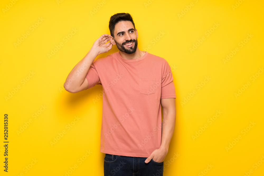 Handsome man over yellow wall thinking an idea while scratching head Handsome man over yellow wall thinking an idea while scratching head