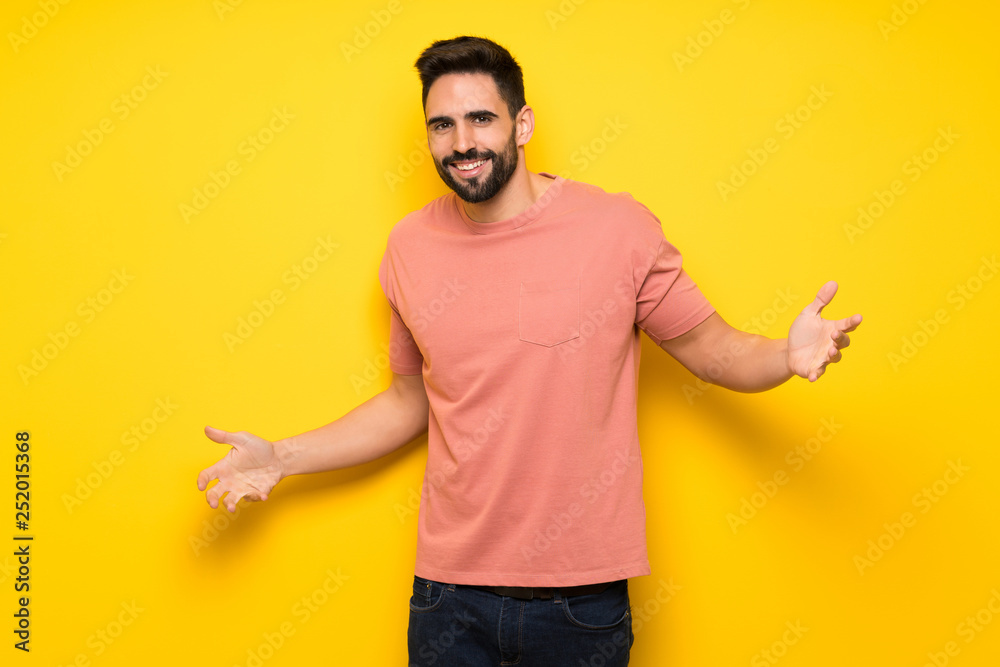 Handsome man over yellow wall proud and self-satisfied in love yourself concept Handsome man over yellow wall proud and self-satisfied in love yourself concept